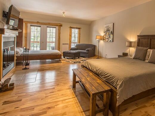 Auberge du Vieux Moulin Lanaudière Luxurious bedroom with king bed and wood fireplace